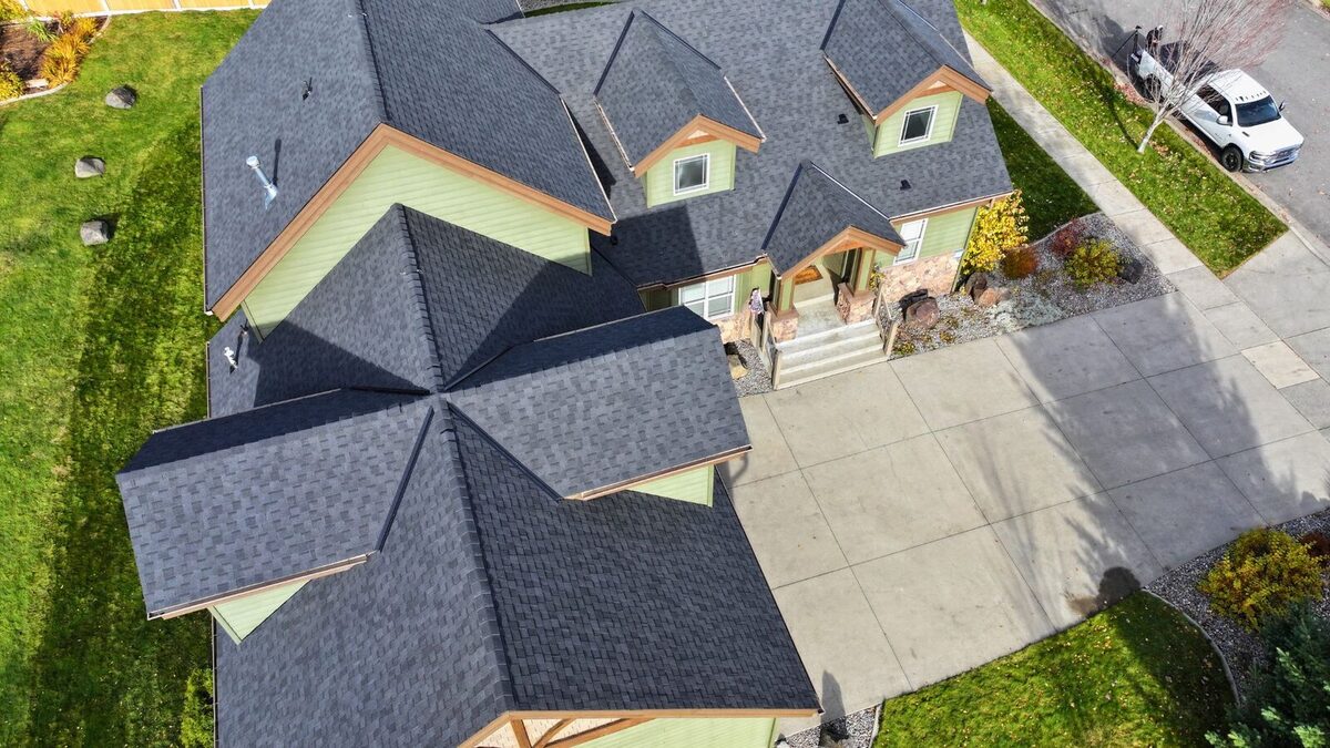 CertainTeed ClimateFlex shingles in Moire Black on a Hayden, Idaho home with sage green siding, cedar trim and a stone entry