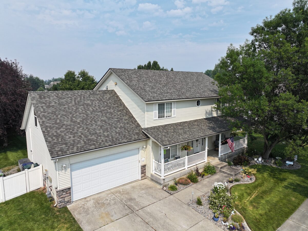 Two story North Idaho home with cream siding and stone accents, roofed in CertainTeed Landmark shingles in Weathered Wood