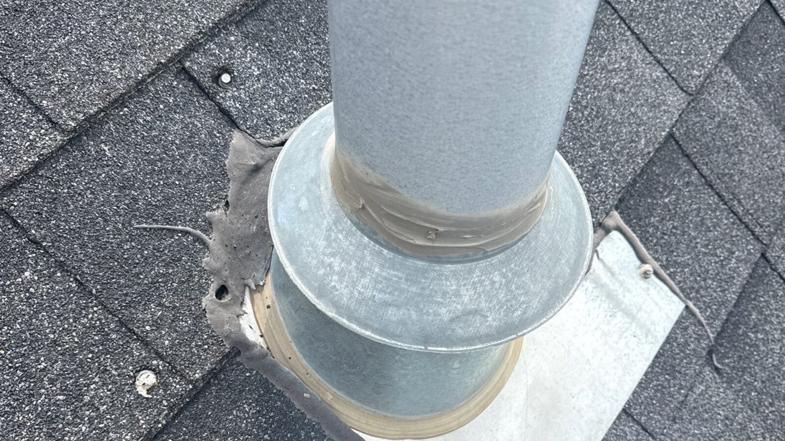 A roof vent flashing screwed on top of the shingles and sealed with caulk, a cheap North Idaho roofing install
