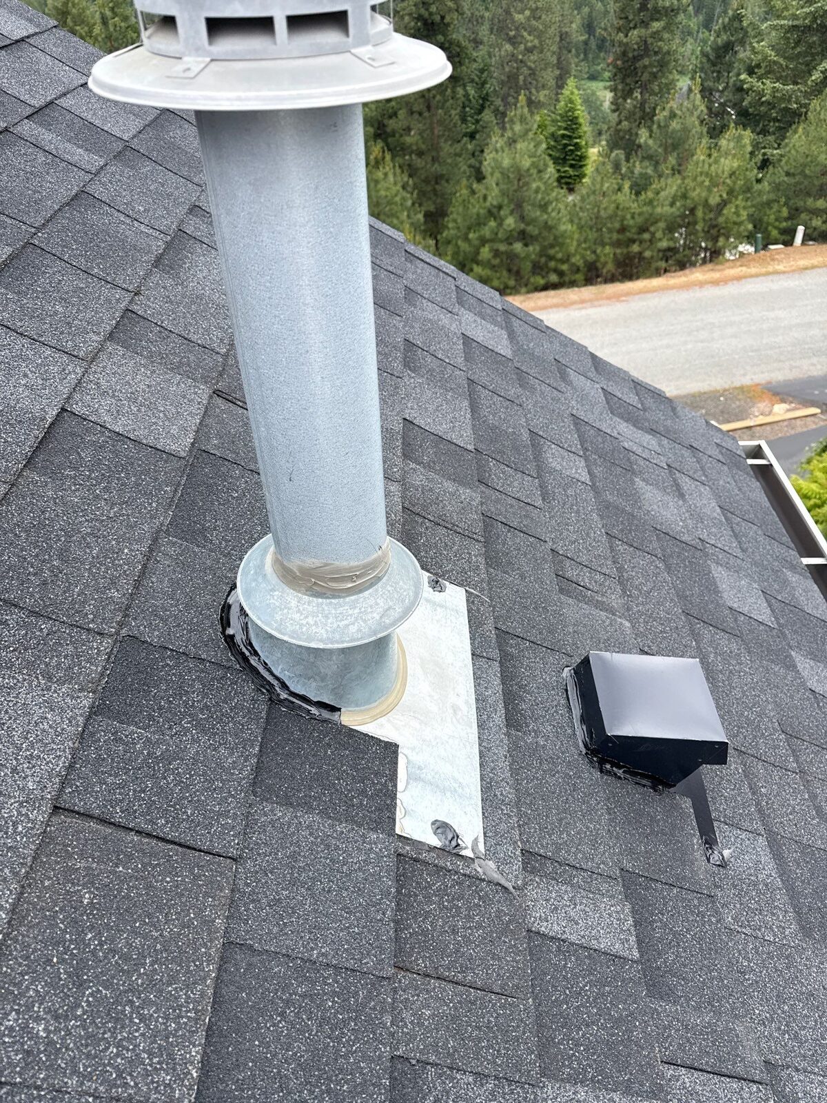The same vent after a proper repair, with the shingles laid back correctly around the flashing to make it watertight