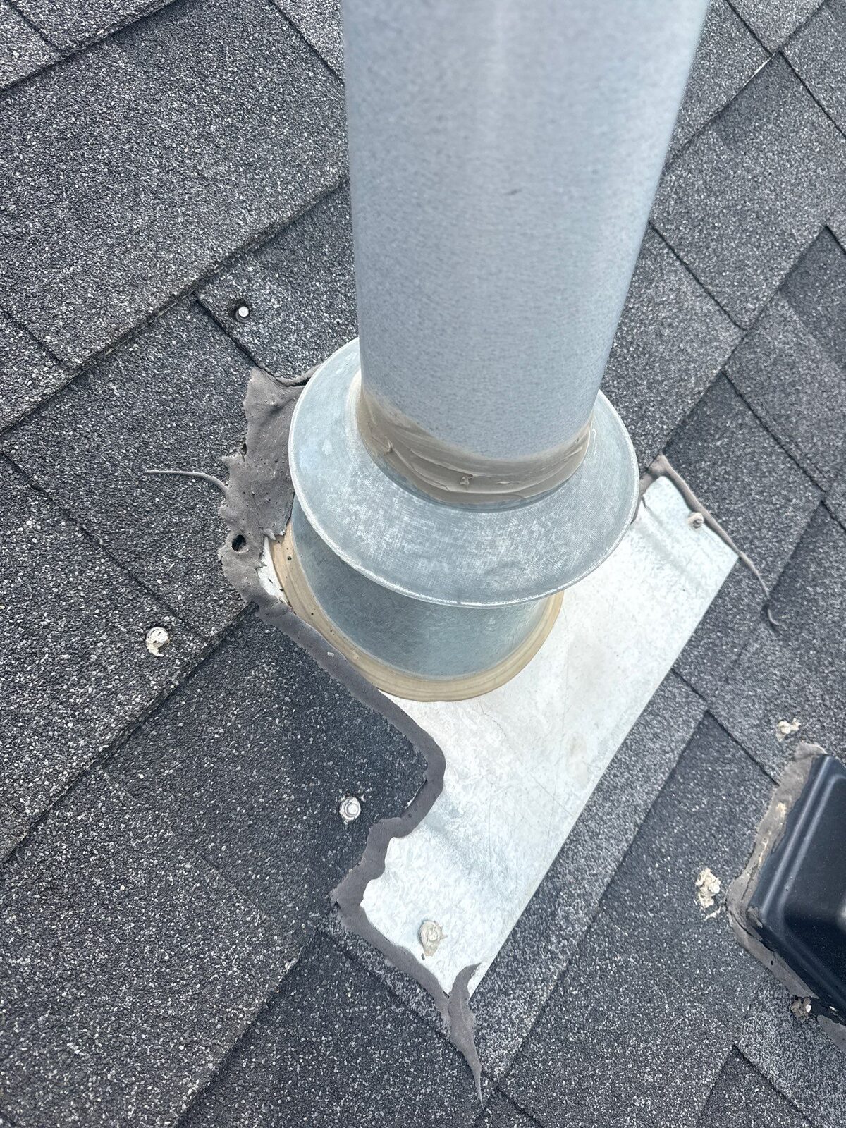 A roof vent on a North Idaho home with screws run straight through it and caulk smeared around the base, instead of the shingles laid correctly around it
