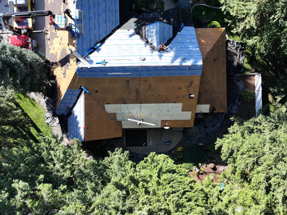 Tear-off in progress on a North Idaho roof replacement, with old shingles removed and the deck exposed