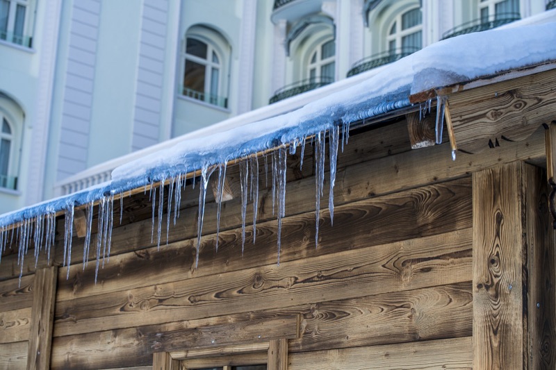 Ice dam with icicles hanging from roof edge