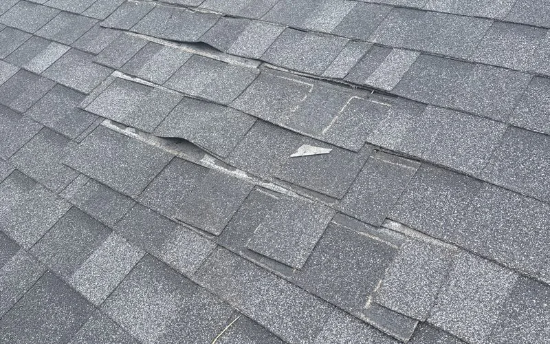 Shingles lifted and displaced across a slope, found during an inspection