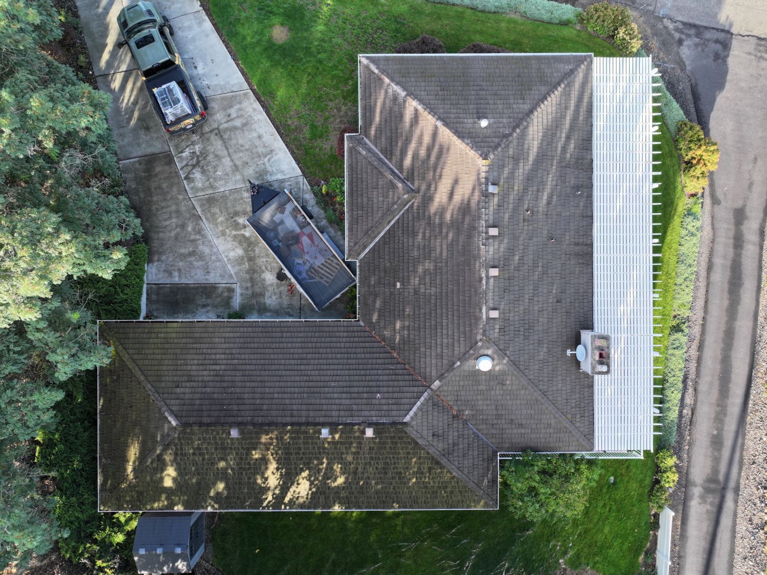 Before: top-down aerial of the old roof showing moss under the trees