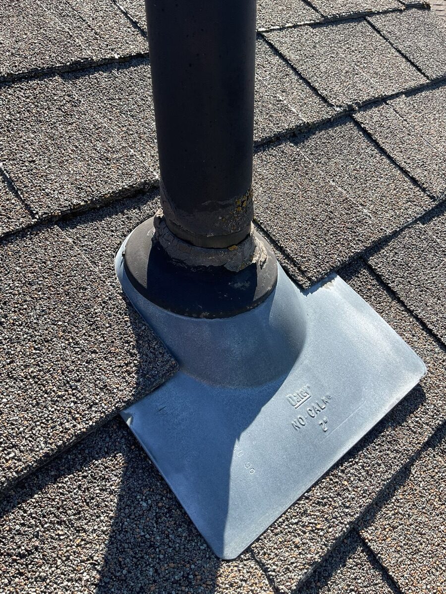 Close-up of worn pipe boot flashing on deteriorating shingles