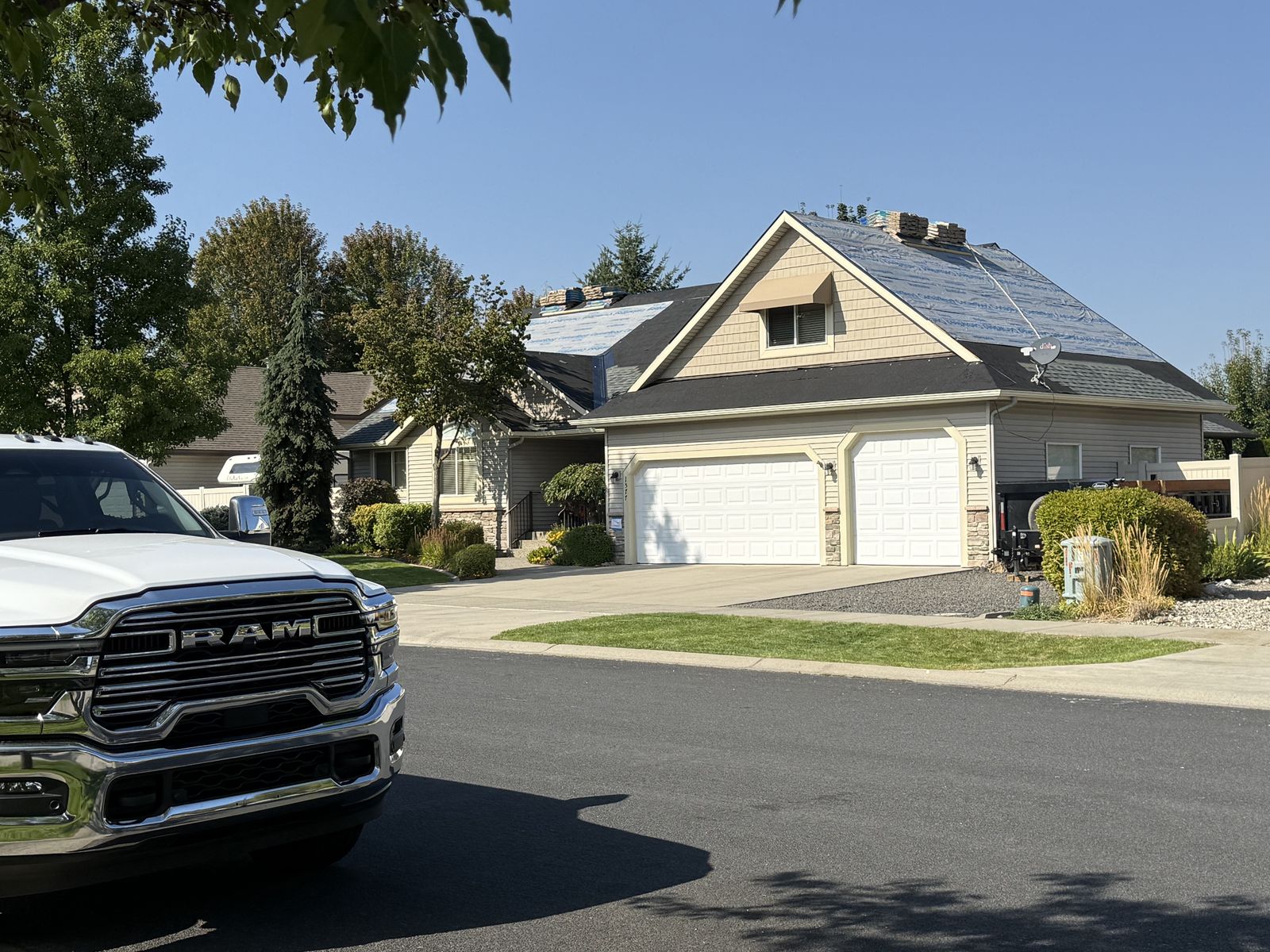Street view of the home during roof replacement with crew working and Elevated Roofing truck on site