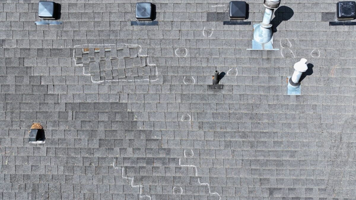 Aerial view of roof with chalk-marked damage areas around pipe boots and vents