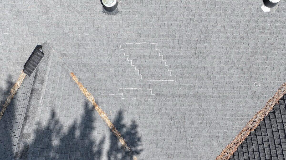 Top-down aerial showing chalk-outlined failed repair patch and pine needle debris in valleys