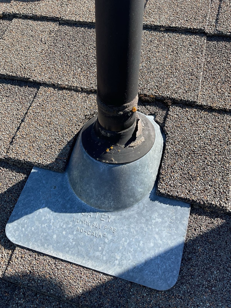 Close-up of aging pipe boot flashing surrounded by granule-depleted shingles