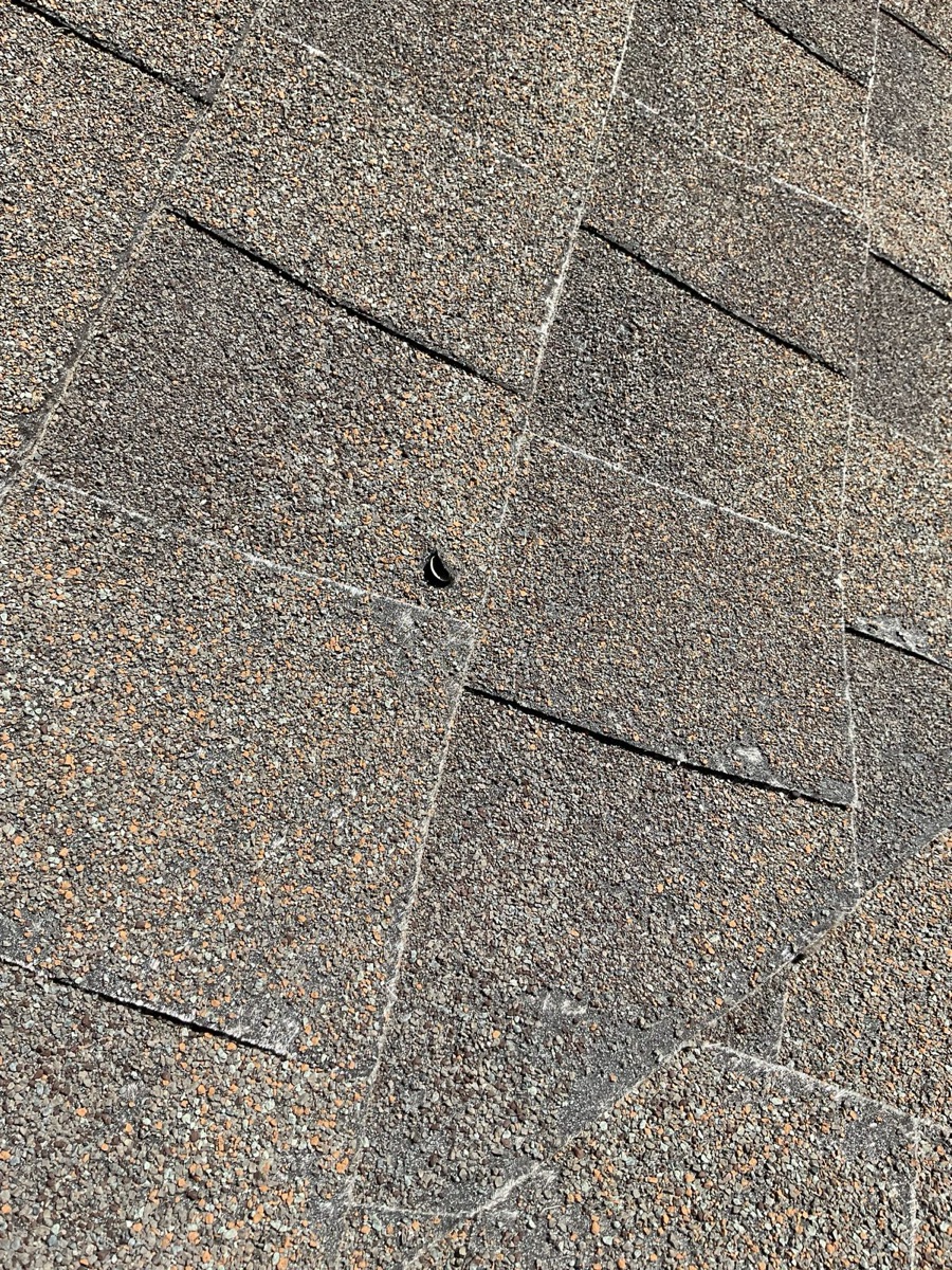 Close-up of cracking shingle tabs with exposed fiberglass and lifting edges
