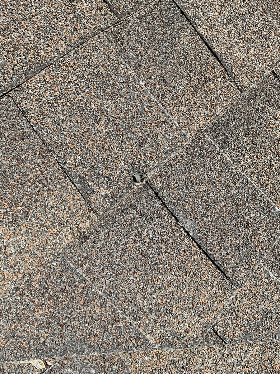 Close-up of worn shingle tabs with heavy granule loss and cracking