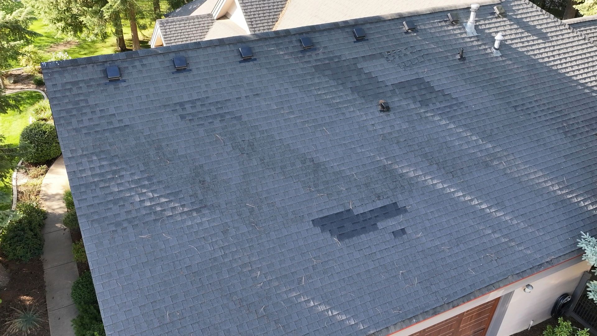 Drone view of roof with missing shingles and exposed underlayment from wind damage