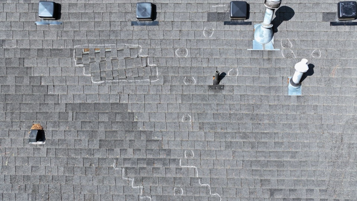 Drone photo of roof with chalk-marked damage areas and pipe boots