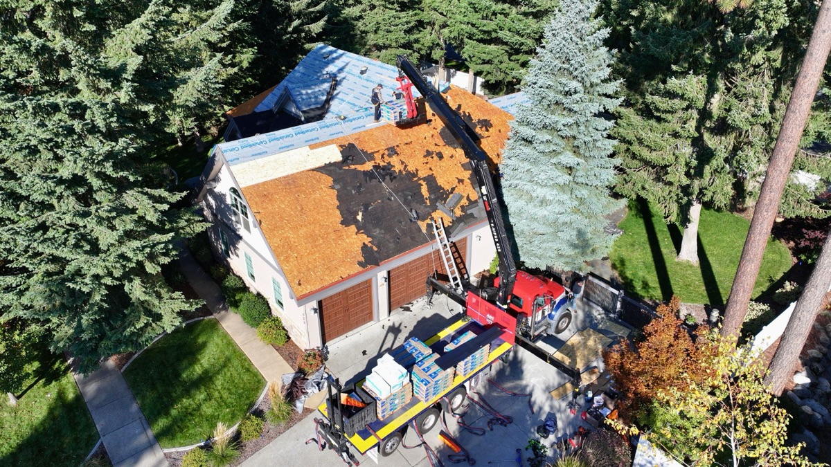 Aerial of tear-off in progress with conveyor loading dump trailer and exposed decking