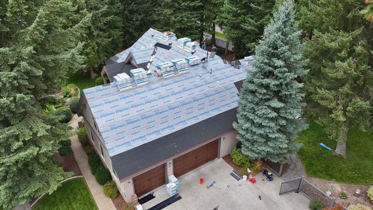 Aerial angled view of underlayment fully installed with material pallets staged near garage