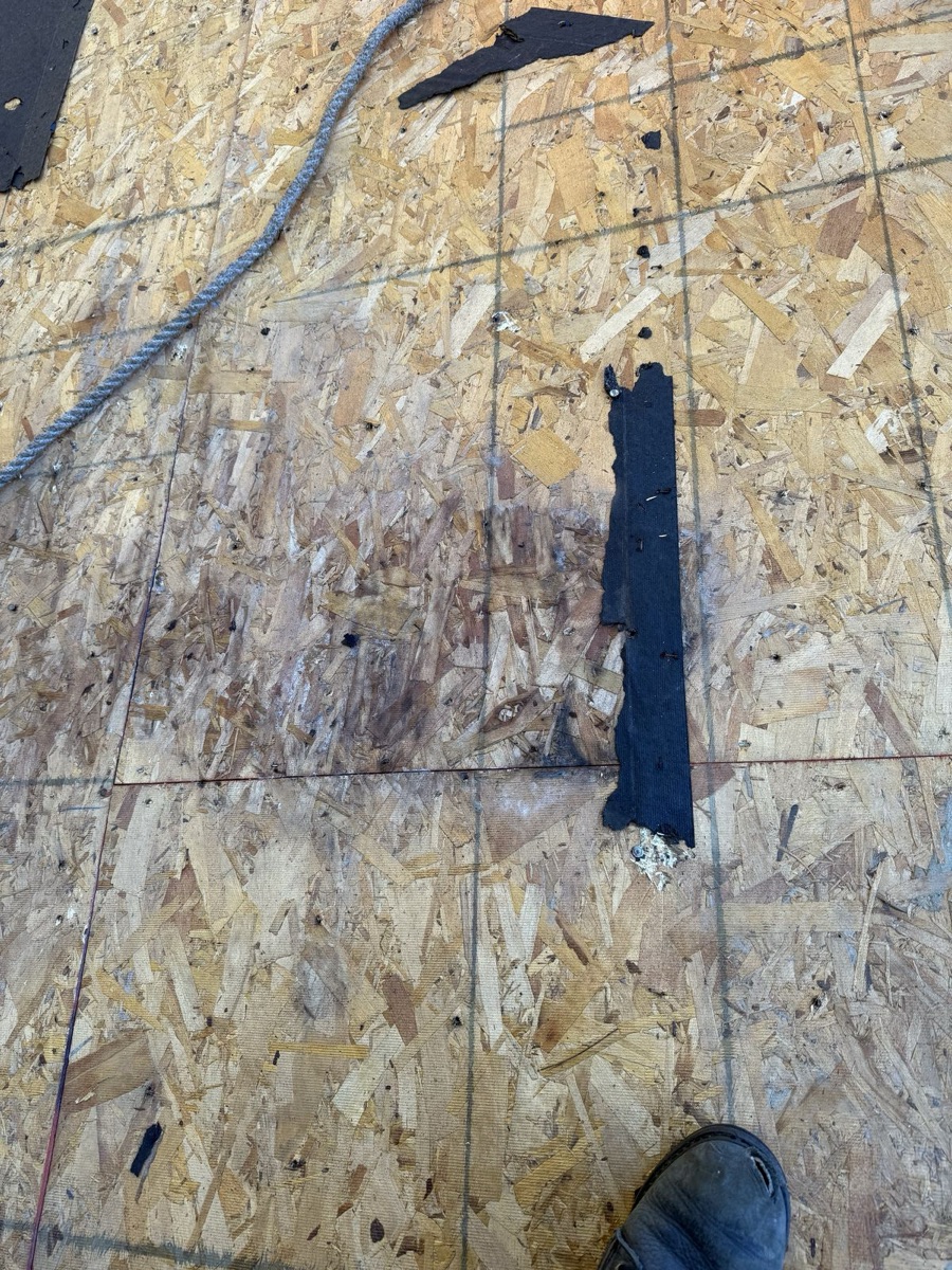 Close-up of water-damaged OSB decking with staining and remnant tar paper