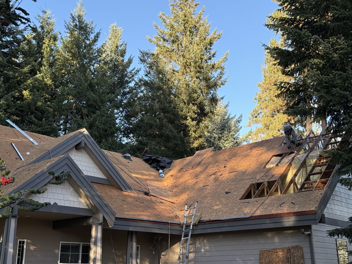 Ground-level view of the house during tear-off with crew working on exposed decking